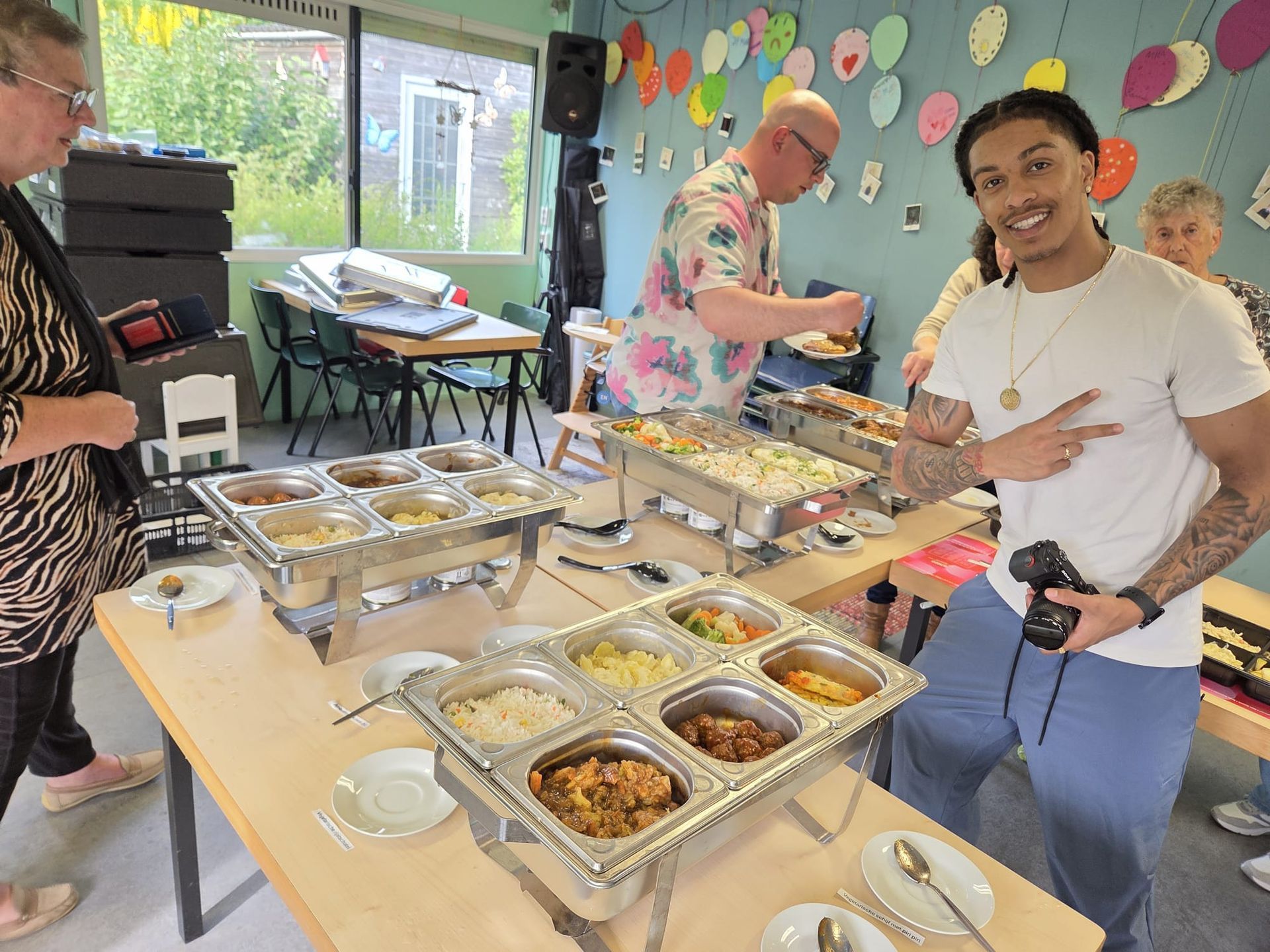 Mensen die een buffet met afgedekte schalen bedienen in een versierde ruimte.