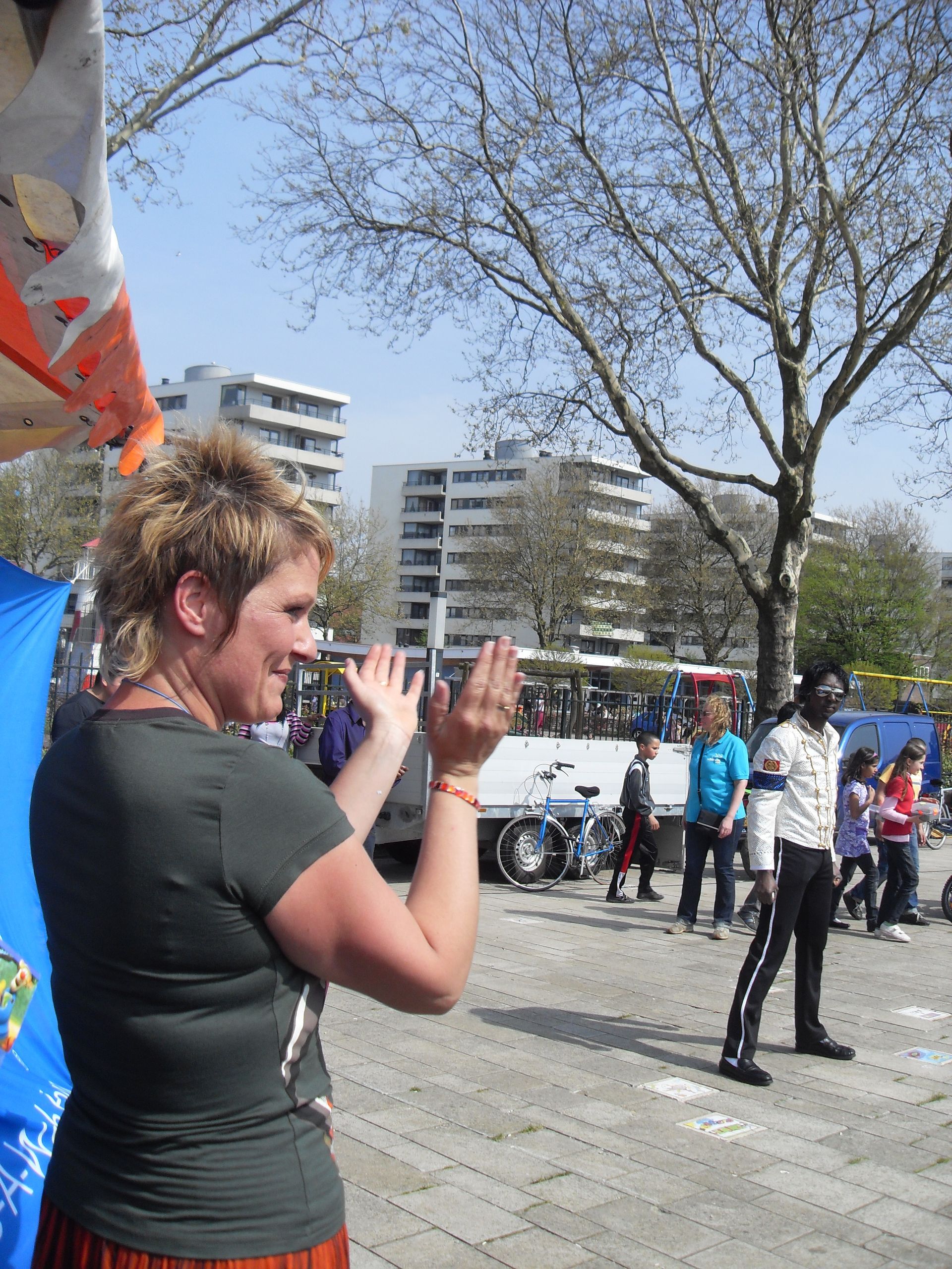 Persoon in donker shirt filmt met een telefoon tijdens een buitenevenement op een zonnige dag.