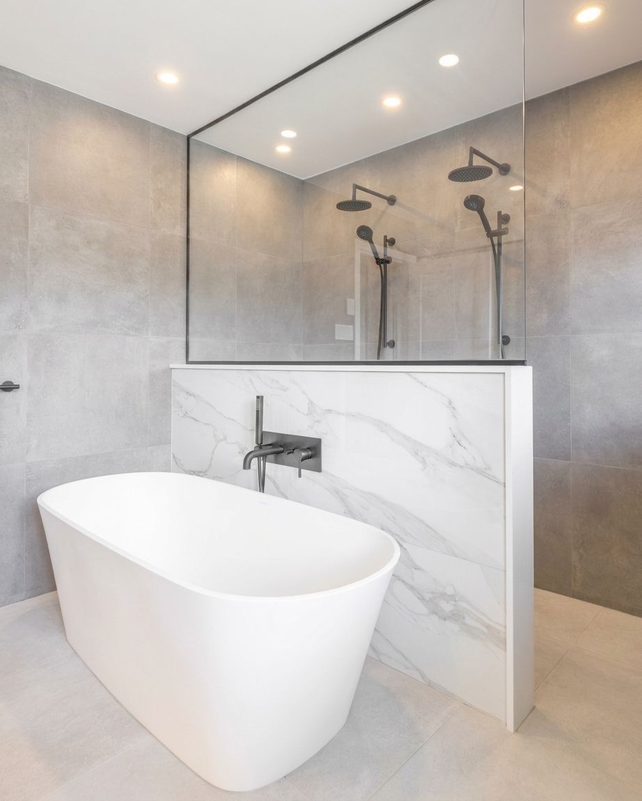 Modern bathroom with freestanding tub, glass shower, and gray marble walls