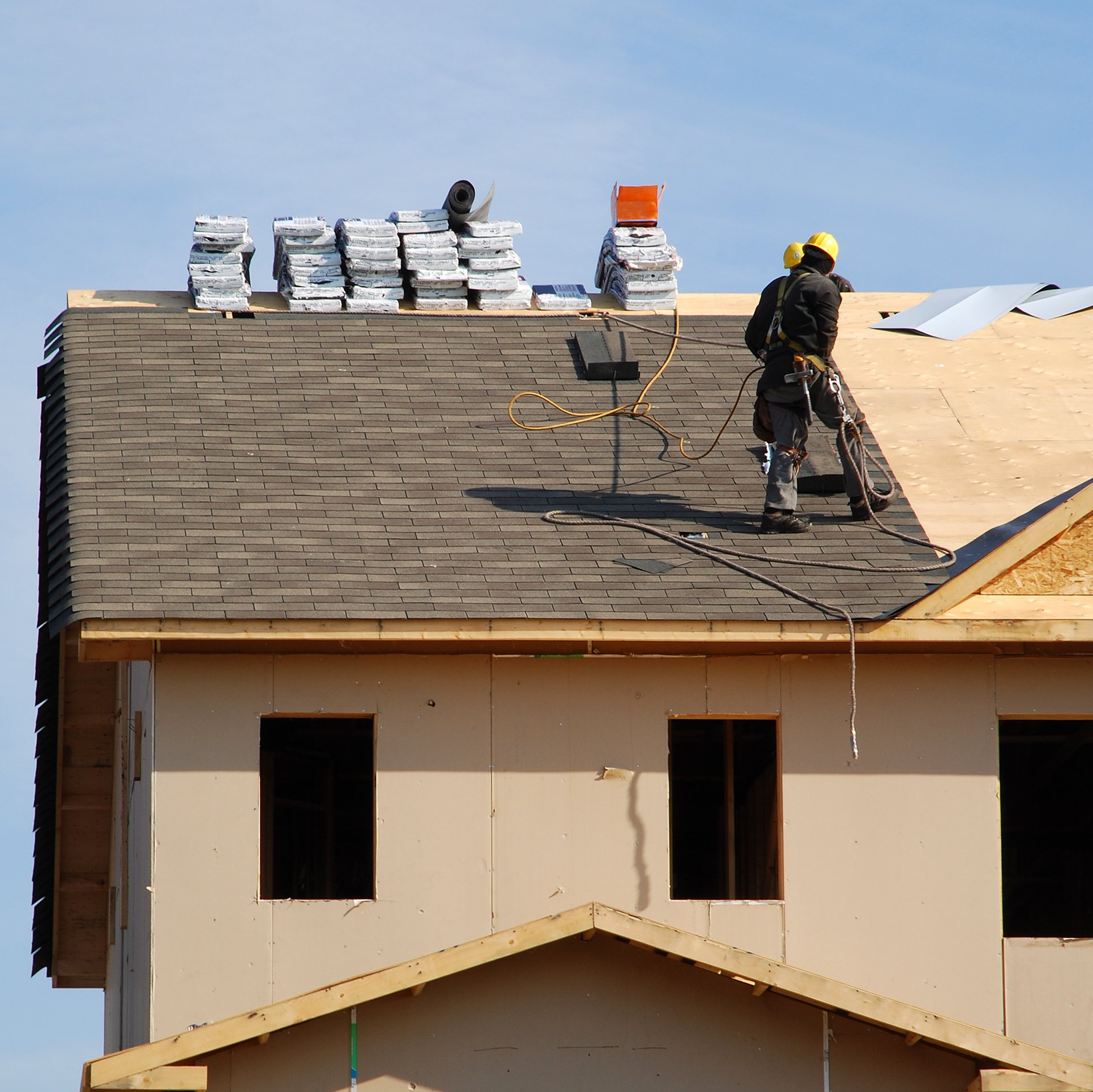 Two men are working on the roof of a house