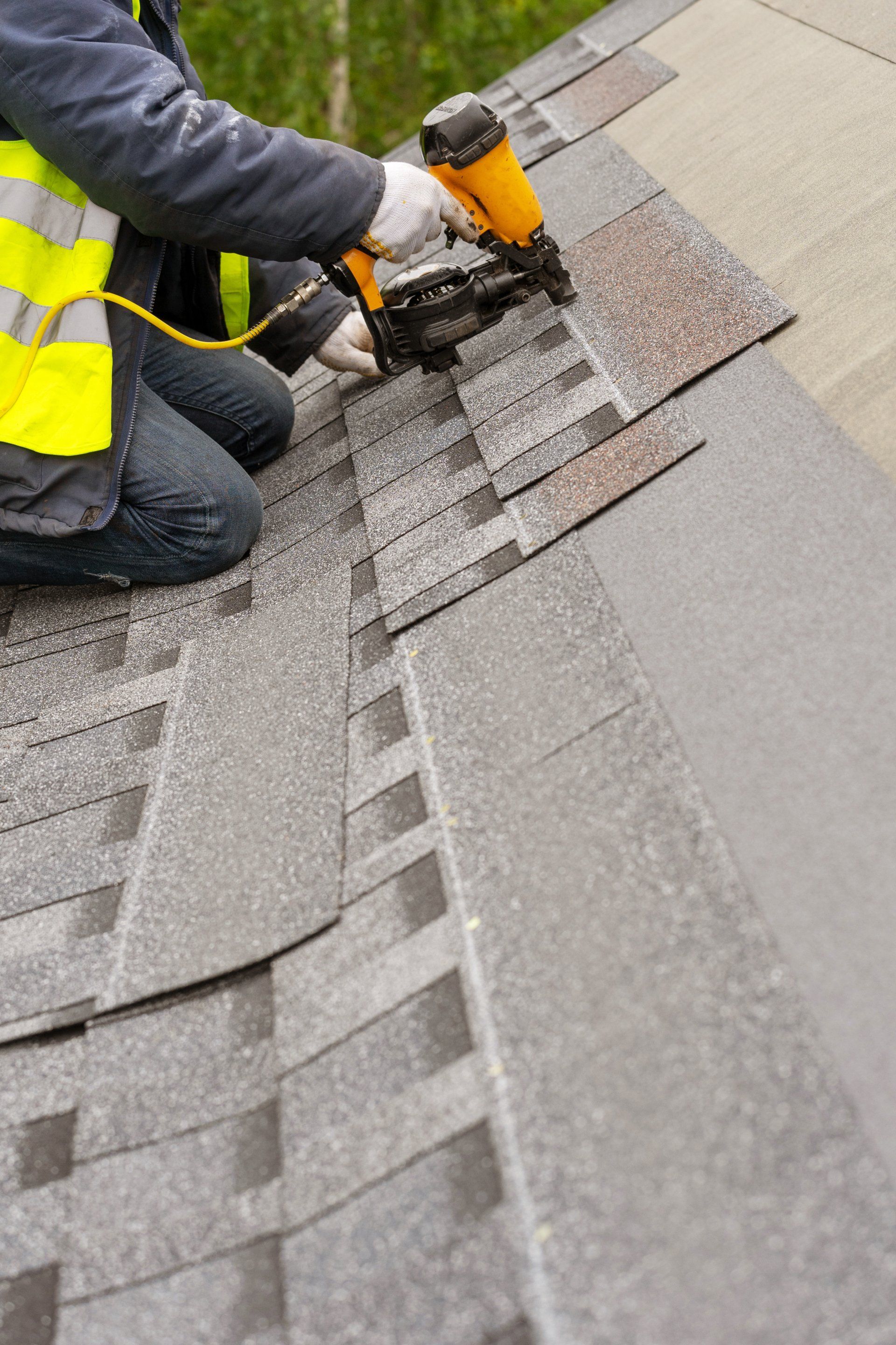 A man is installing shingles on a roof.