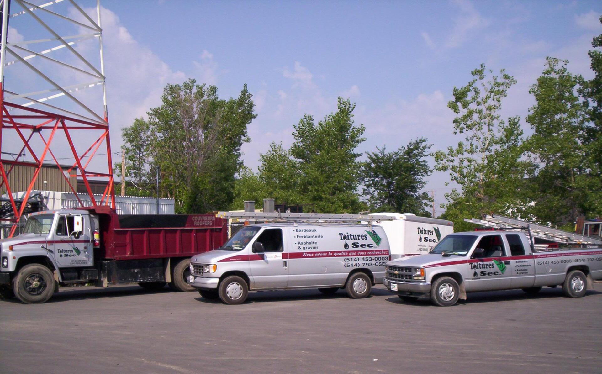 Two trucks and a van are parked in a parking lot