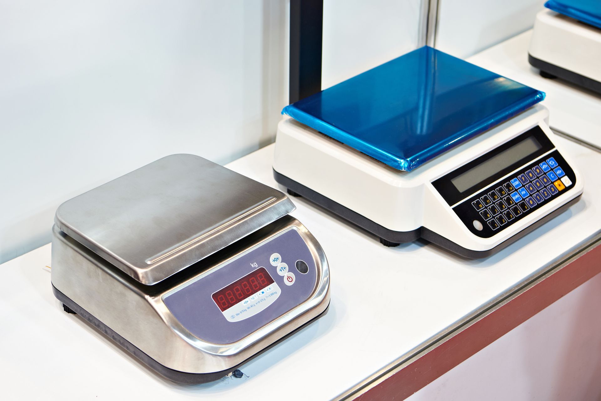 Two digital weighing scales on a countertop, one silver and one blue-lit black scale.