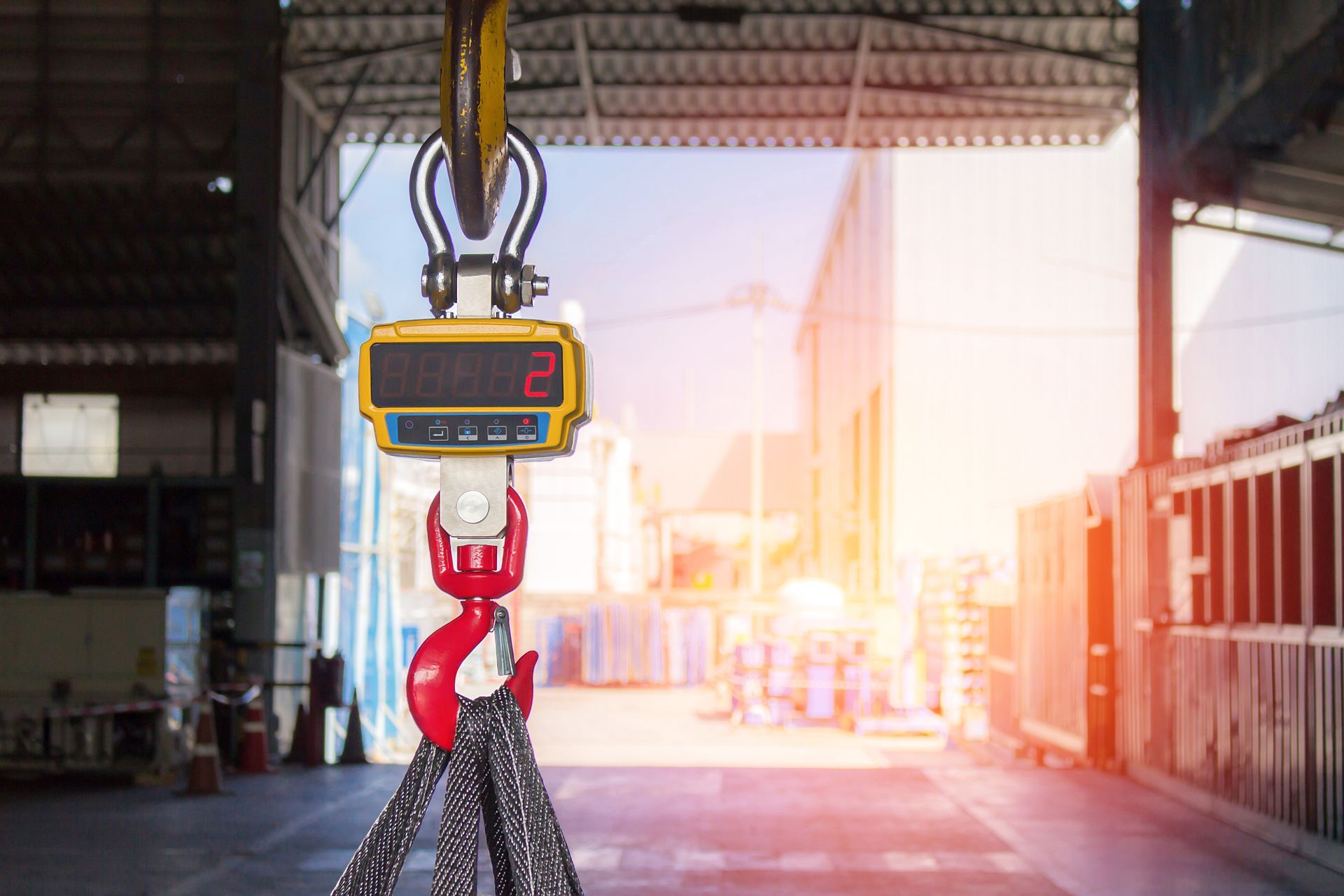 Industrial crane scale with digital display hanging in a warehouse facility.