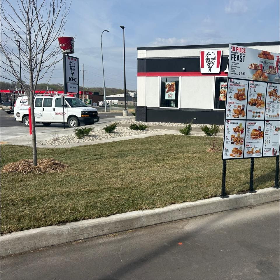 Fast-food restaurant drive-thru with menu board, white van, and grassy parking lot on a cloudy day