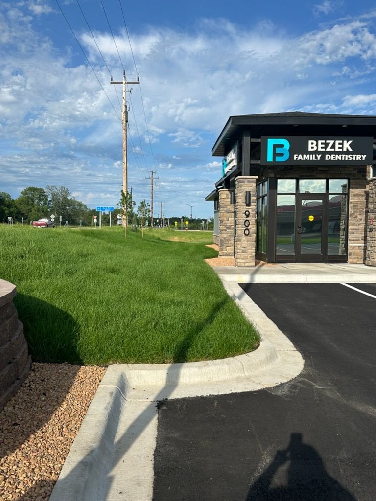 Bezek Mortgage office entrance beside a grassy slope and parking lot under a partly cloudy sky