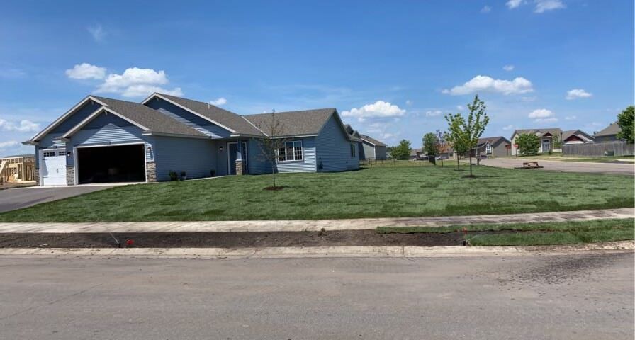 Suburban house with a garage and large grassy yard on a sunny day
