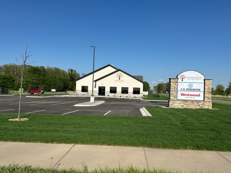 Church building with sign and empty parking lot under a clear blue sky