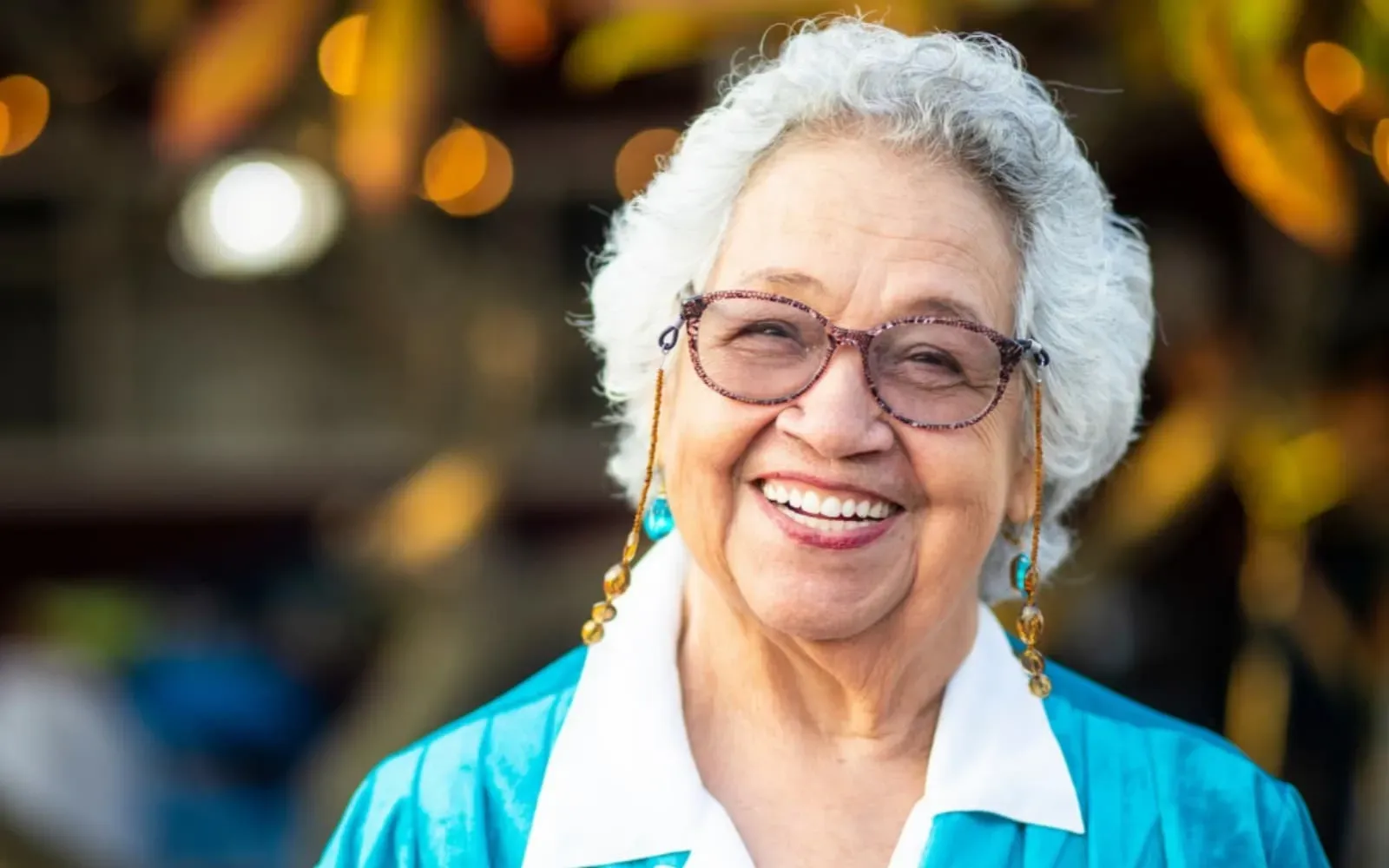 Smiling senior woman wearing glasses, illustrating the benefits of retirement living and senior well-being.