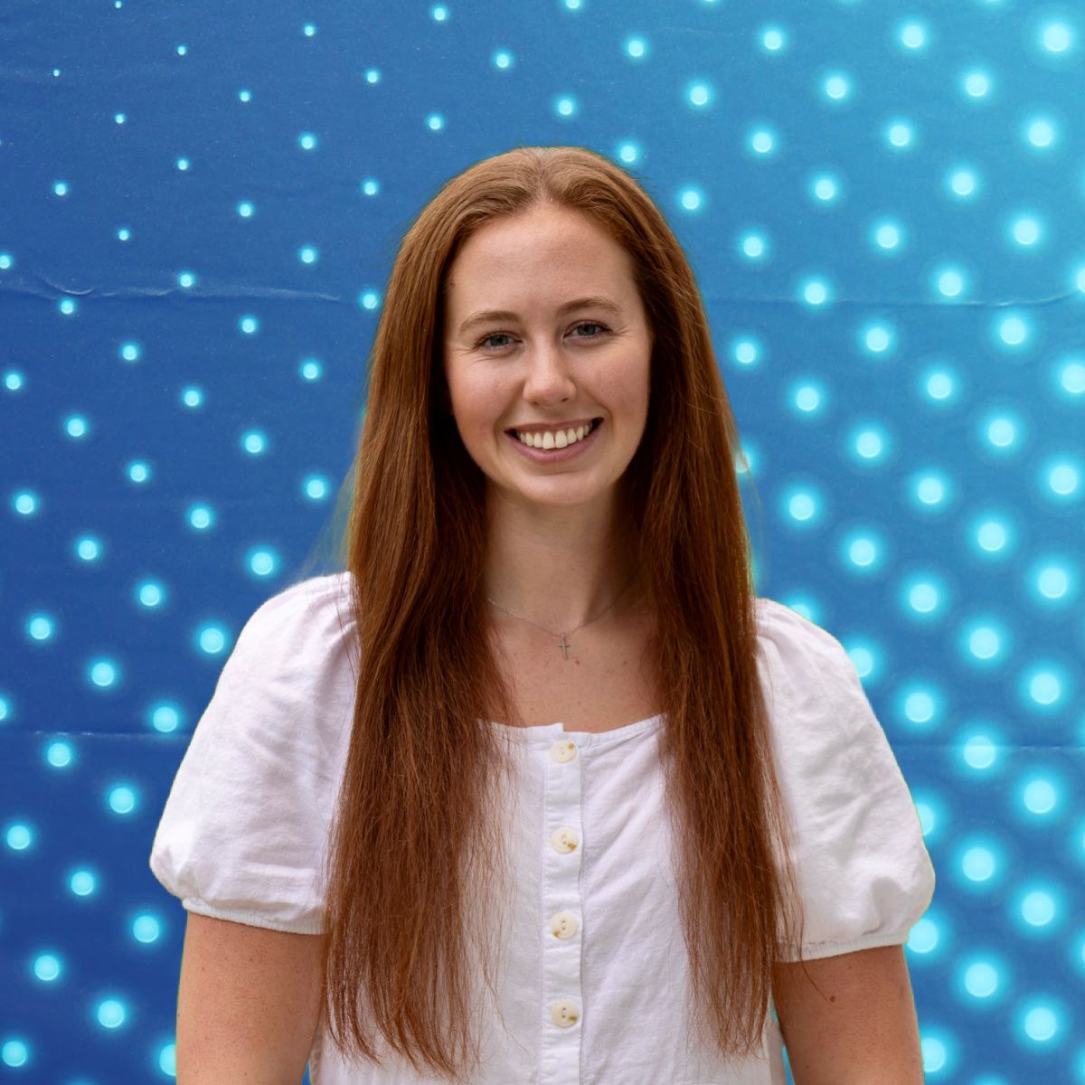 Smiling woman in a white blouse standing against a blue dotted abstract background