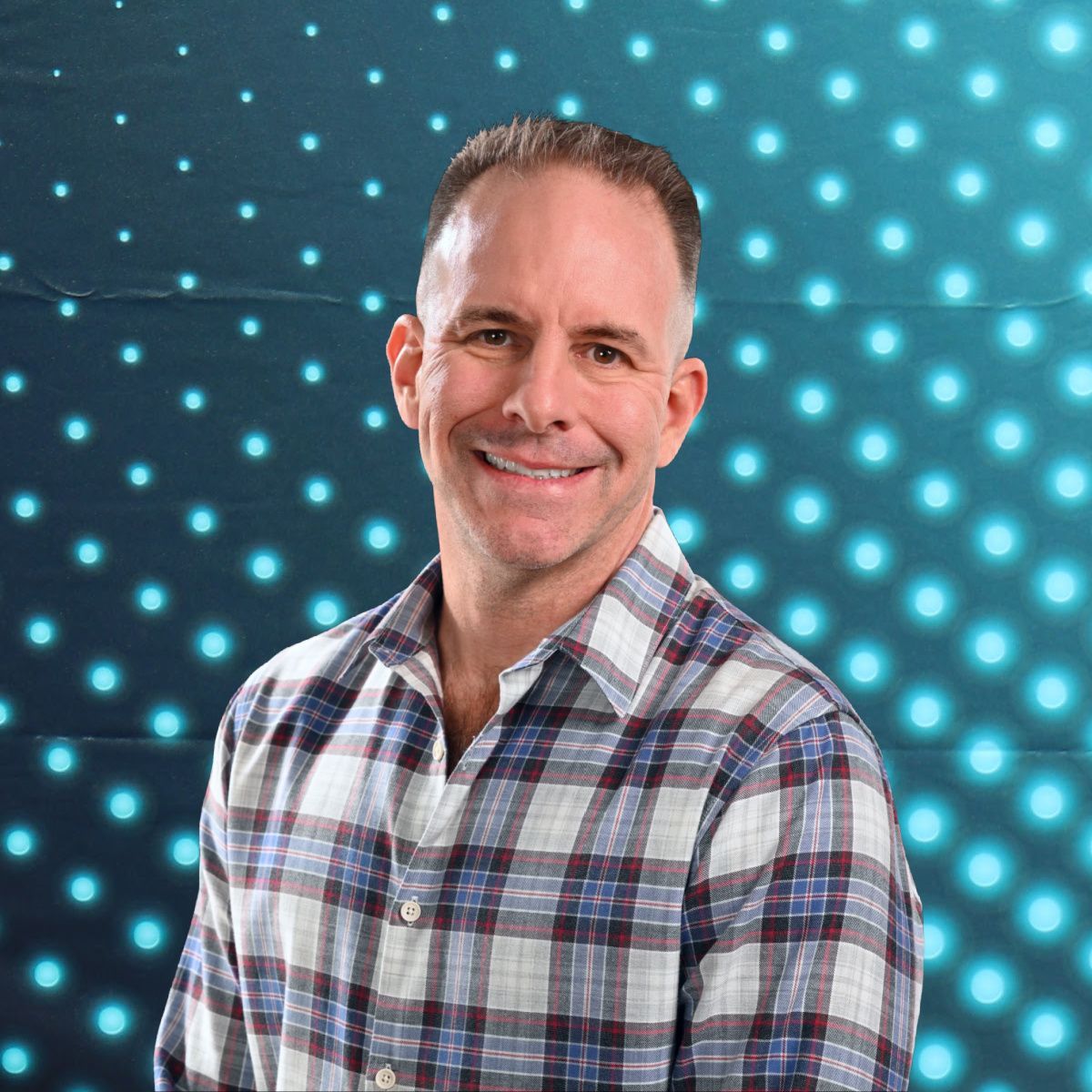Smiling man in plaid shirt against a blue dotted abstract background