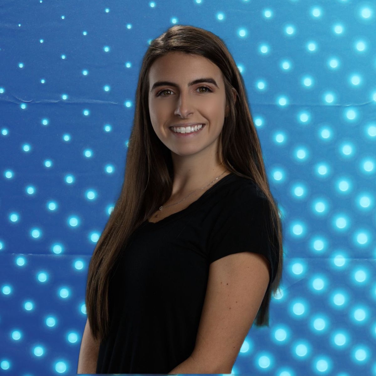 Smiling woman in a black shirt standing before a blue dotted light background