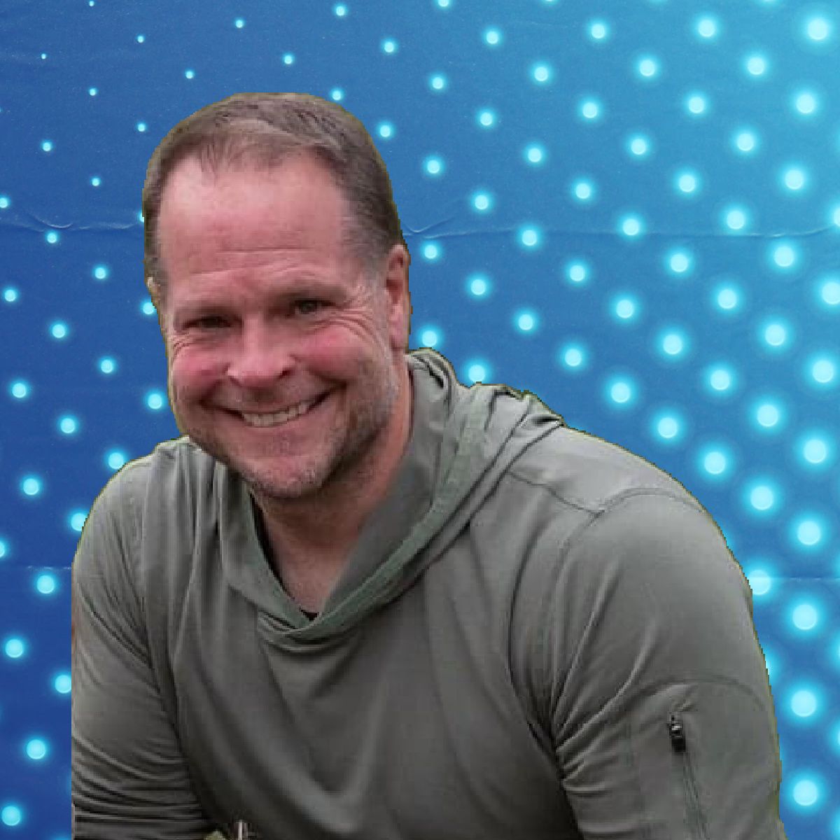 Smiling man in a gray hoodie against a blue dotted light background