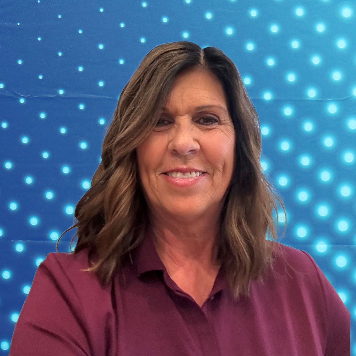 Smiling woman in a maroon shirt against a blue dotted background