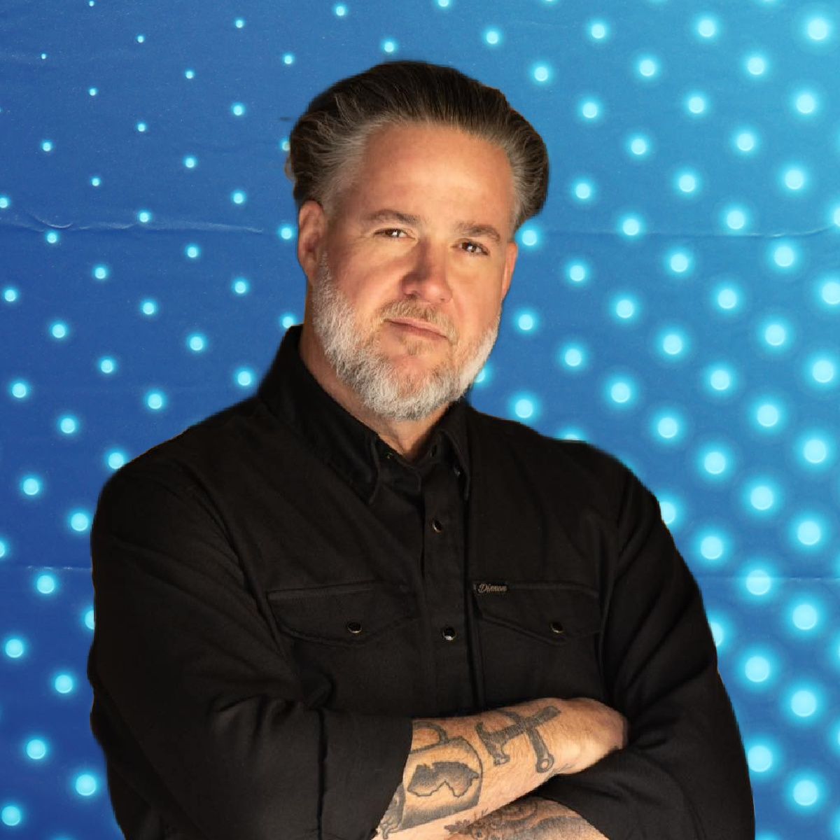 Man with folded arms in a black shirt against a blue dotted background