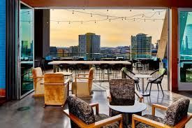 Balcony lounge with wicker chairs, string lights, and city skyline at sunset