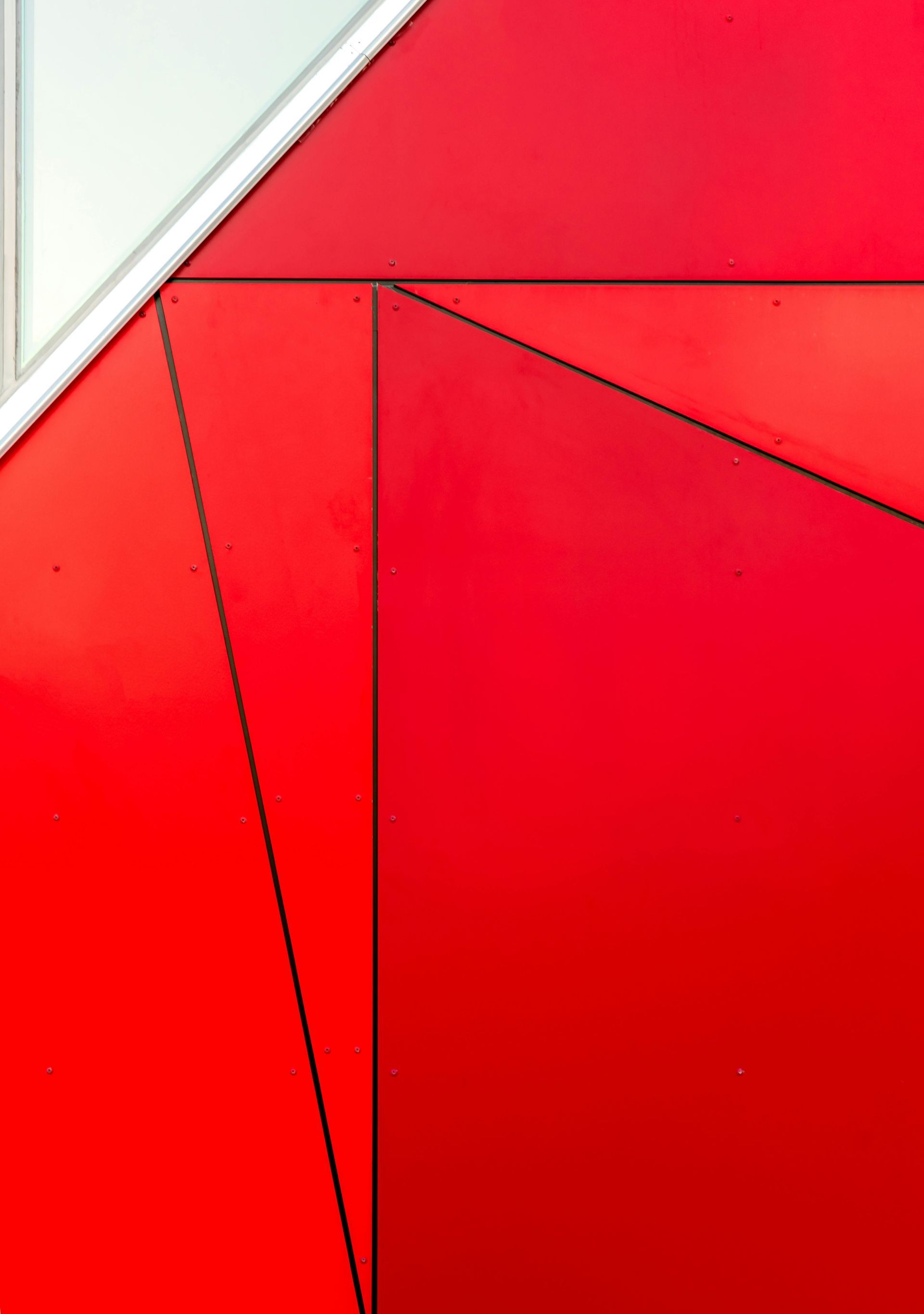 Abstract red geometric surface with black lines and a small white triangle in the corner
