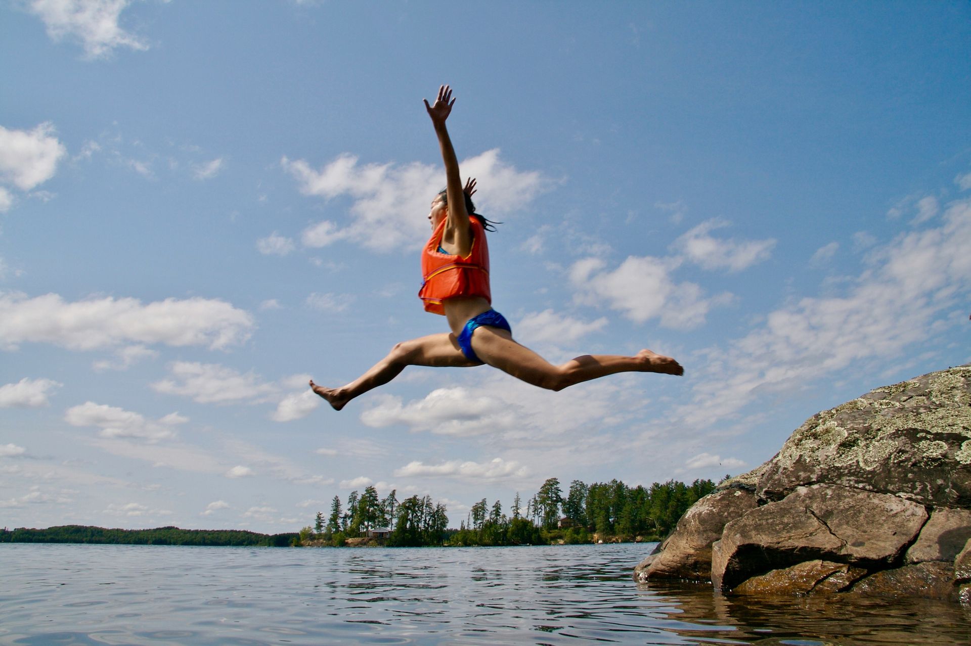 Girl Jumping With Orange Life Jacket