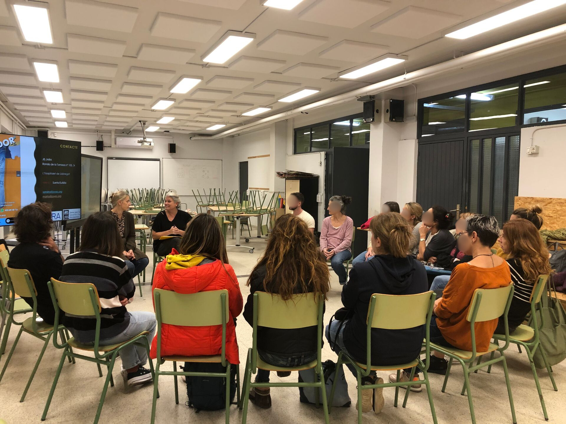Un grup de persones en cercle en una aula, immerses en una discussió.