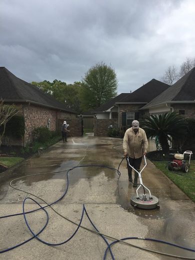 A man is cleaning a driveway with a machine.
