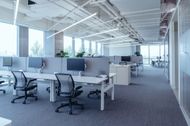 An empty office with a lot of windows and desks and chairs.