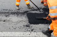 A group of construction workers are working on a road.