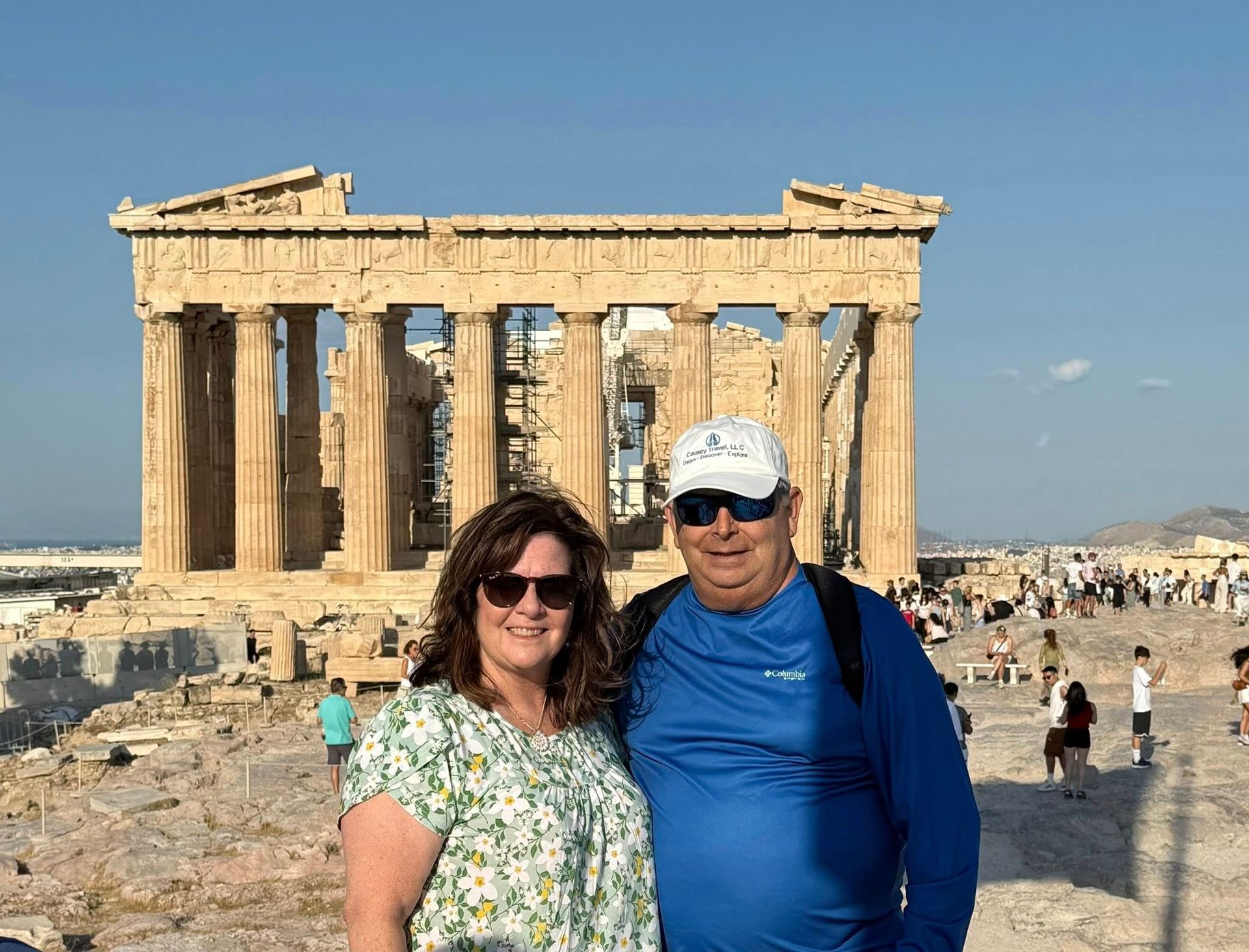 Couple poses in front of the Parthenon in Athens, Greece, on a sunny day.