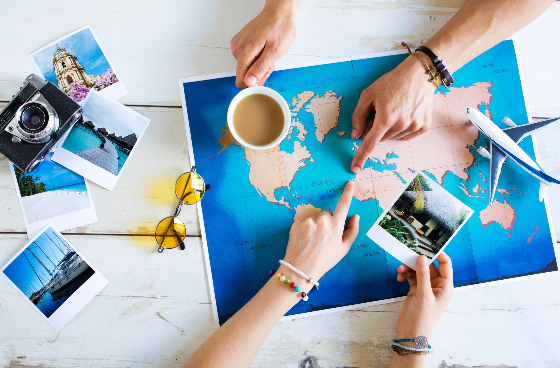 Travel planning with a world map, photos, airplane model, and coffee on a table