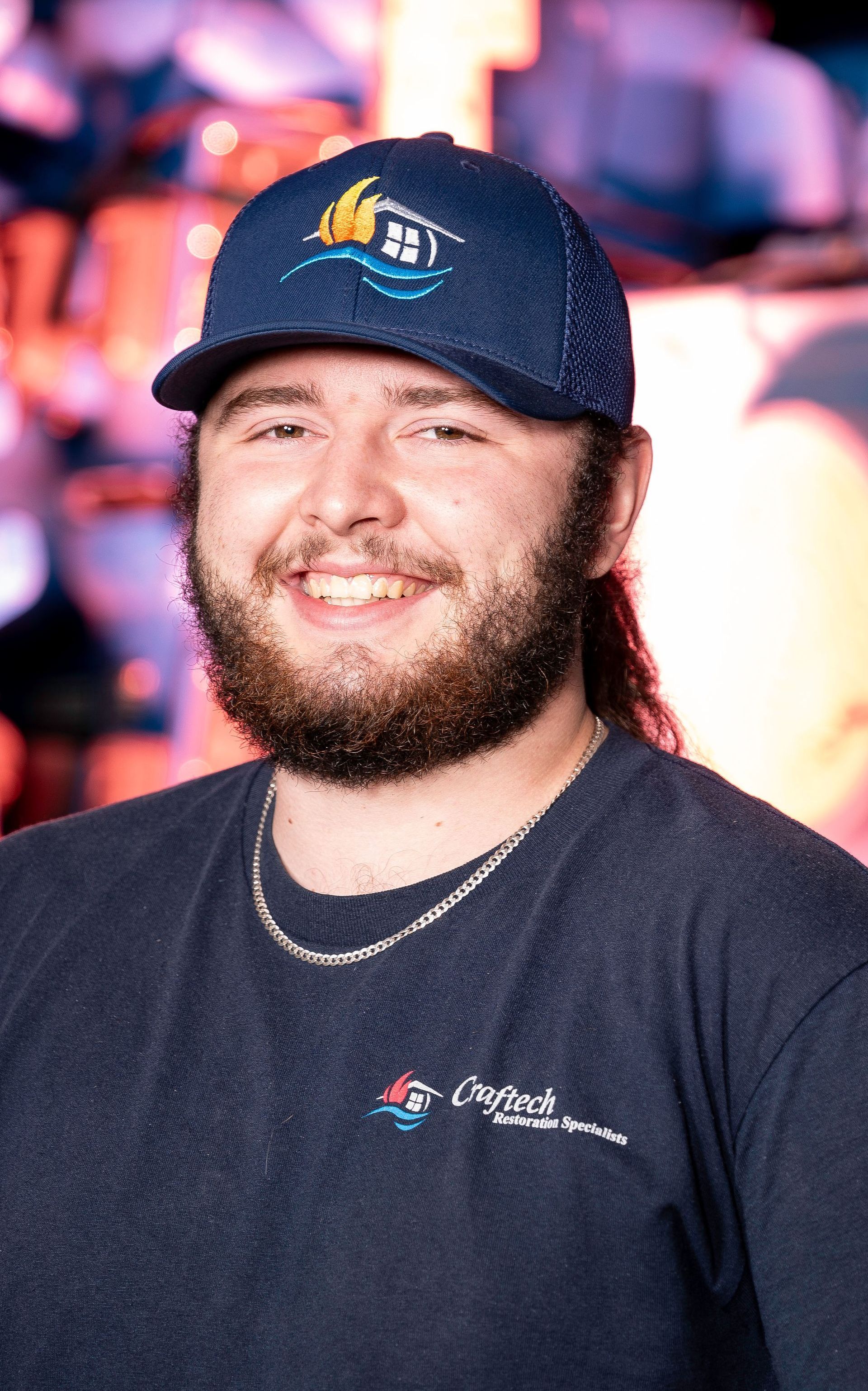 A man with a beard is wearing a blue hat and smiling.