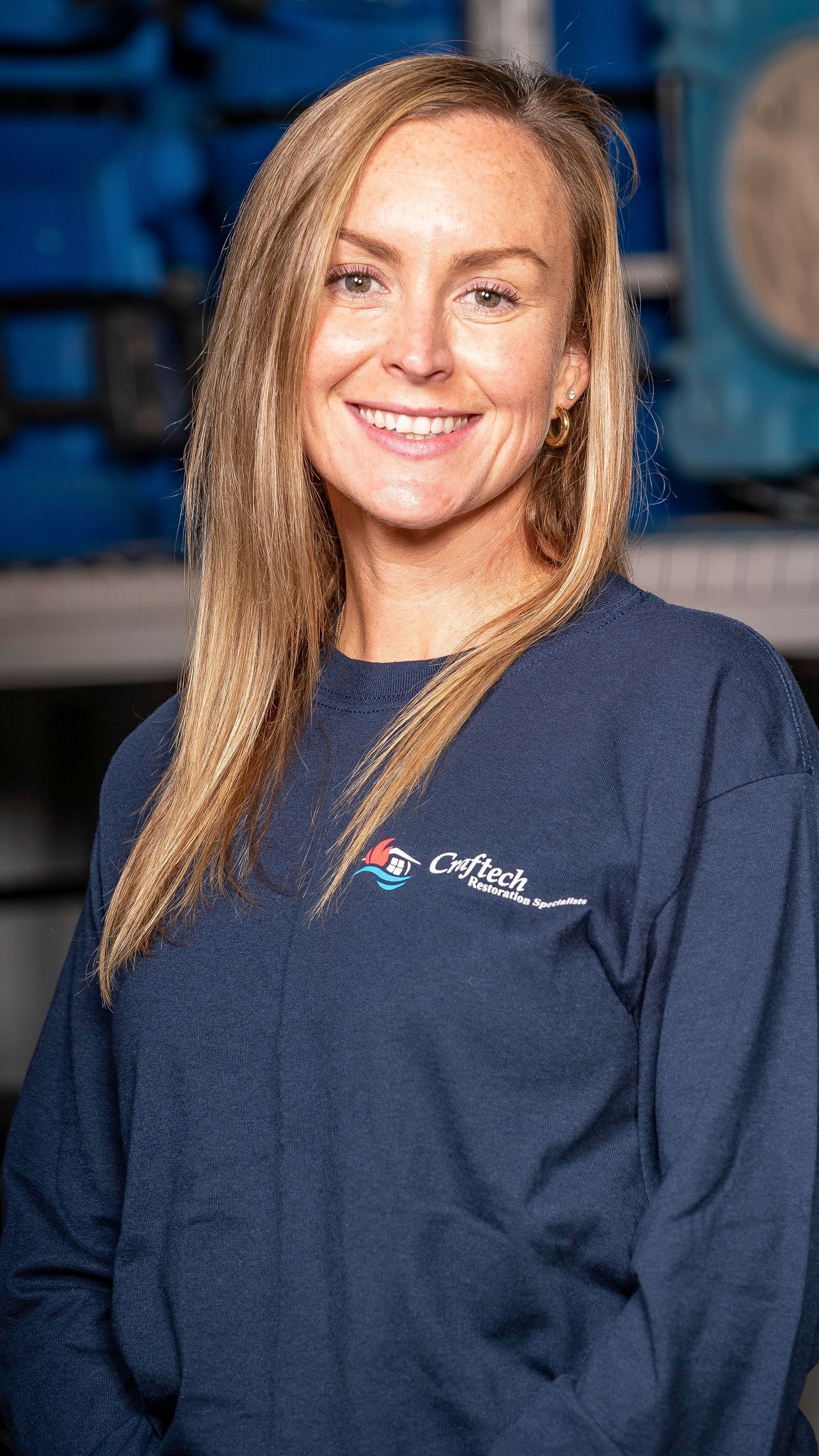 A woman is wearing a blue sweater and smiling for the camera.