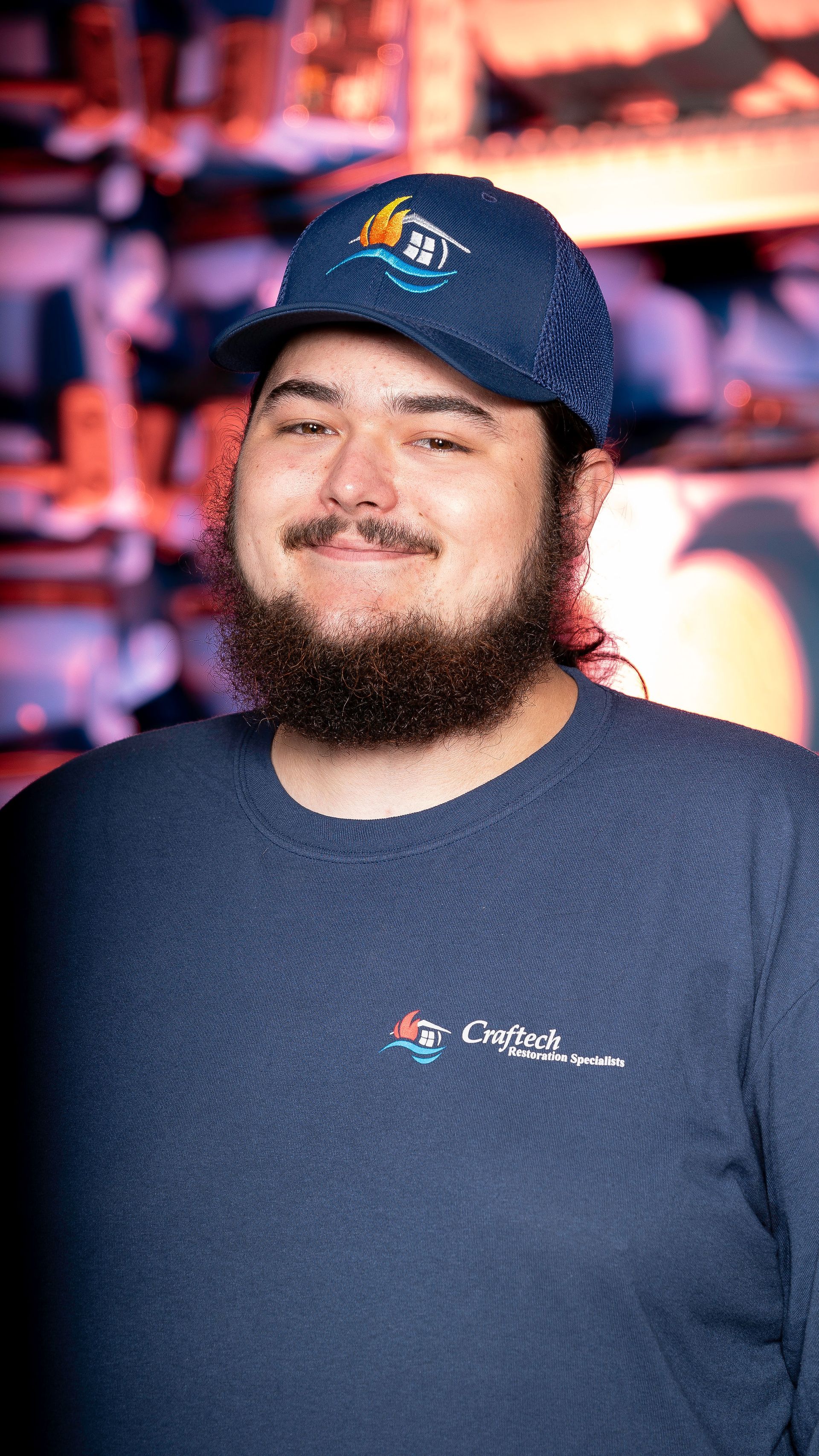 A man with a beard is wearing a hat and a blue shirt.