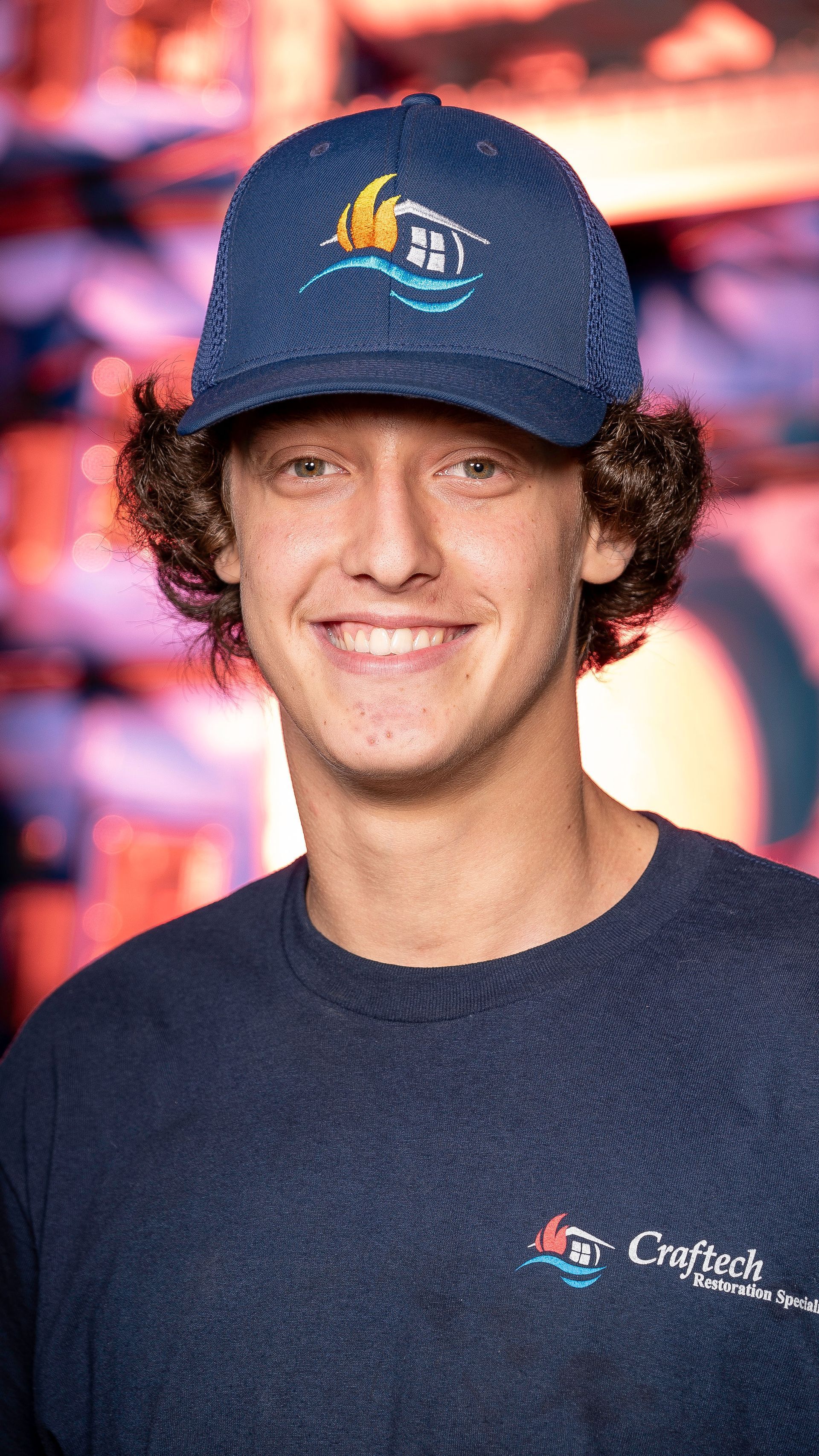 A young man wearing a blue hat and a blue t-shirt is smiling for the camera.