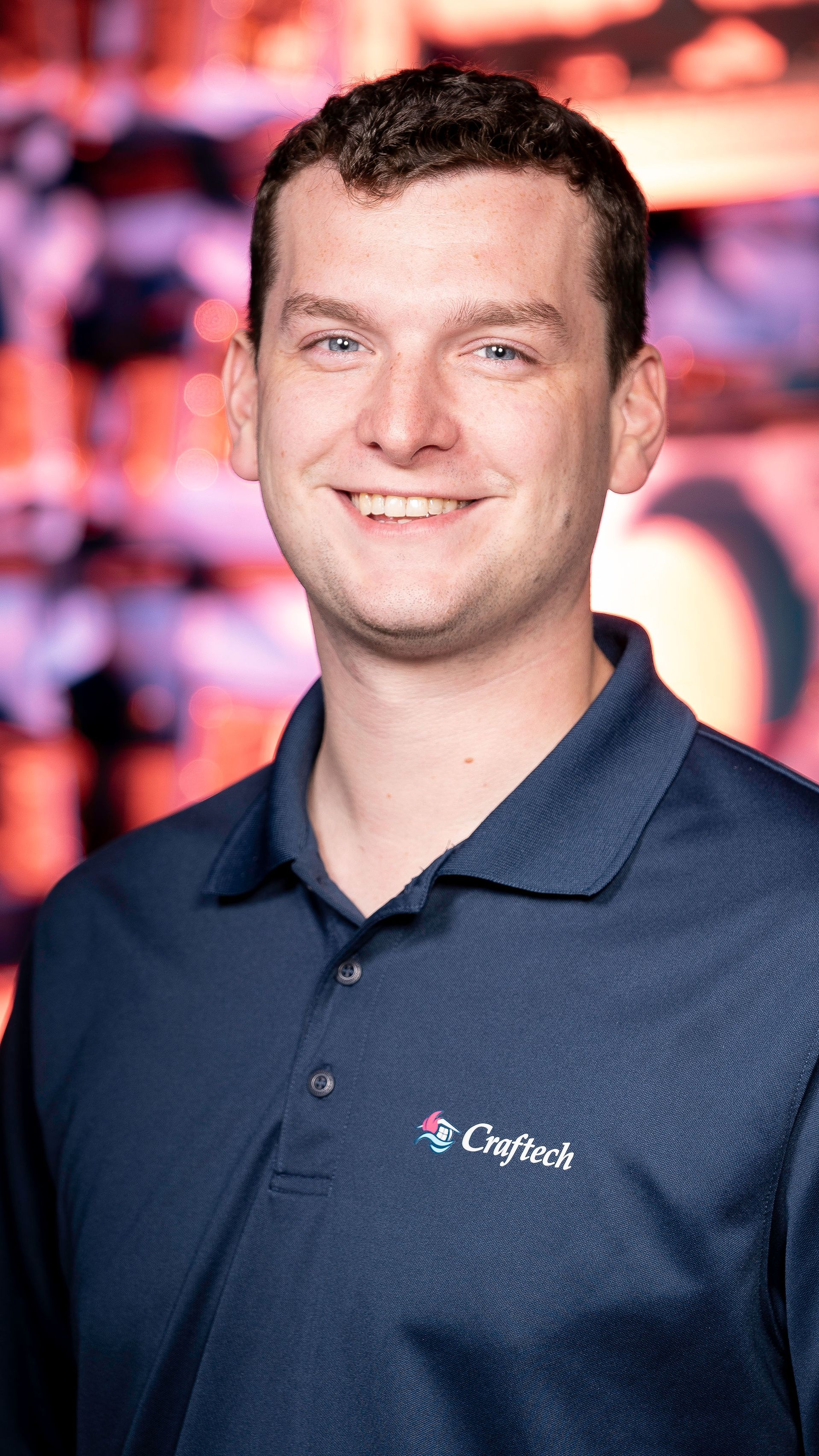 A man in a blue polo shirt is smiling for the camera.