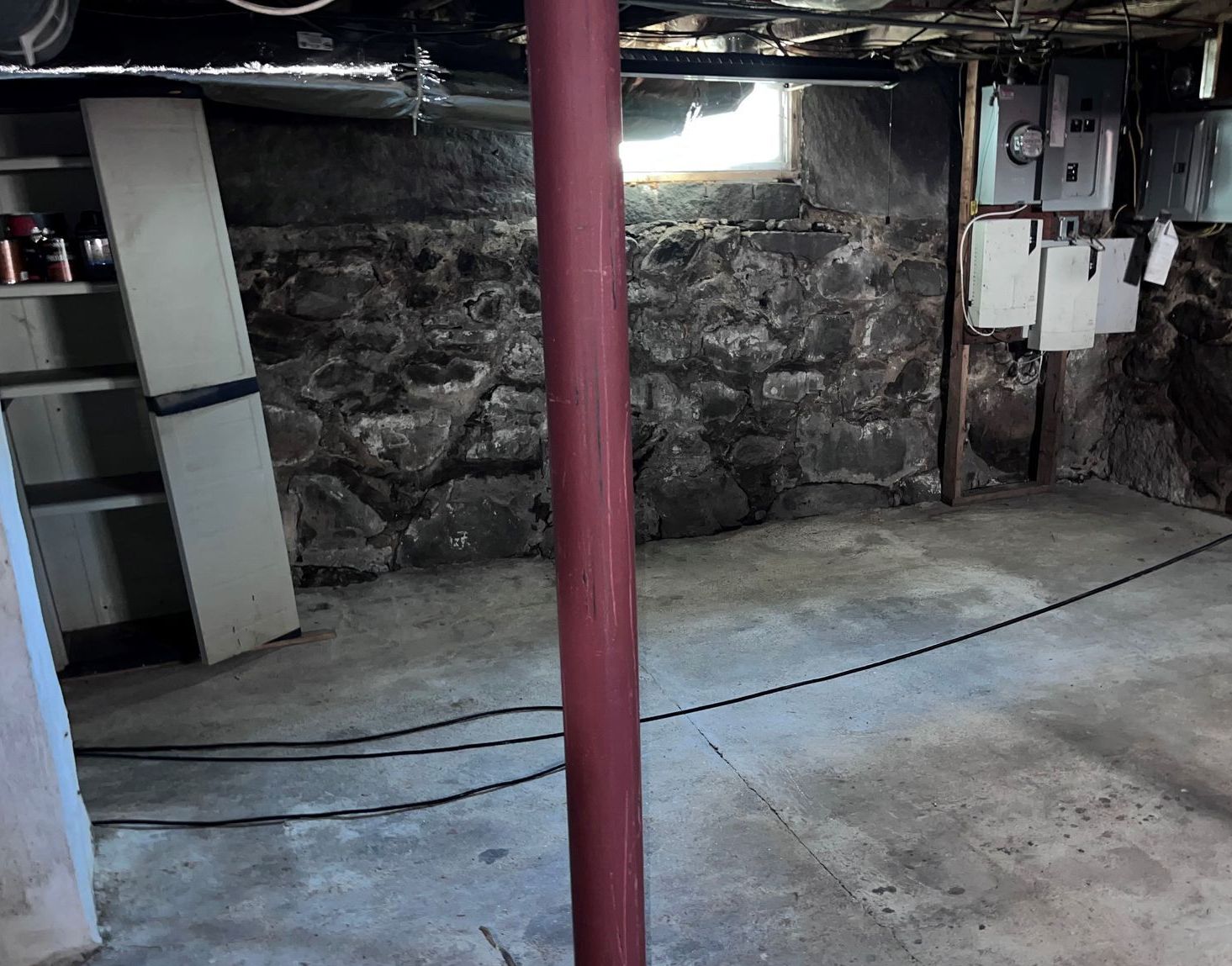 An empty basement with a red pole in the middle