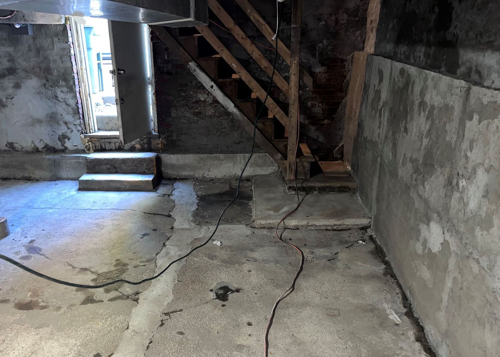 A basement with stairs and a wooden railing