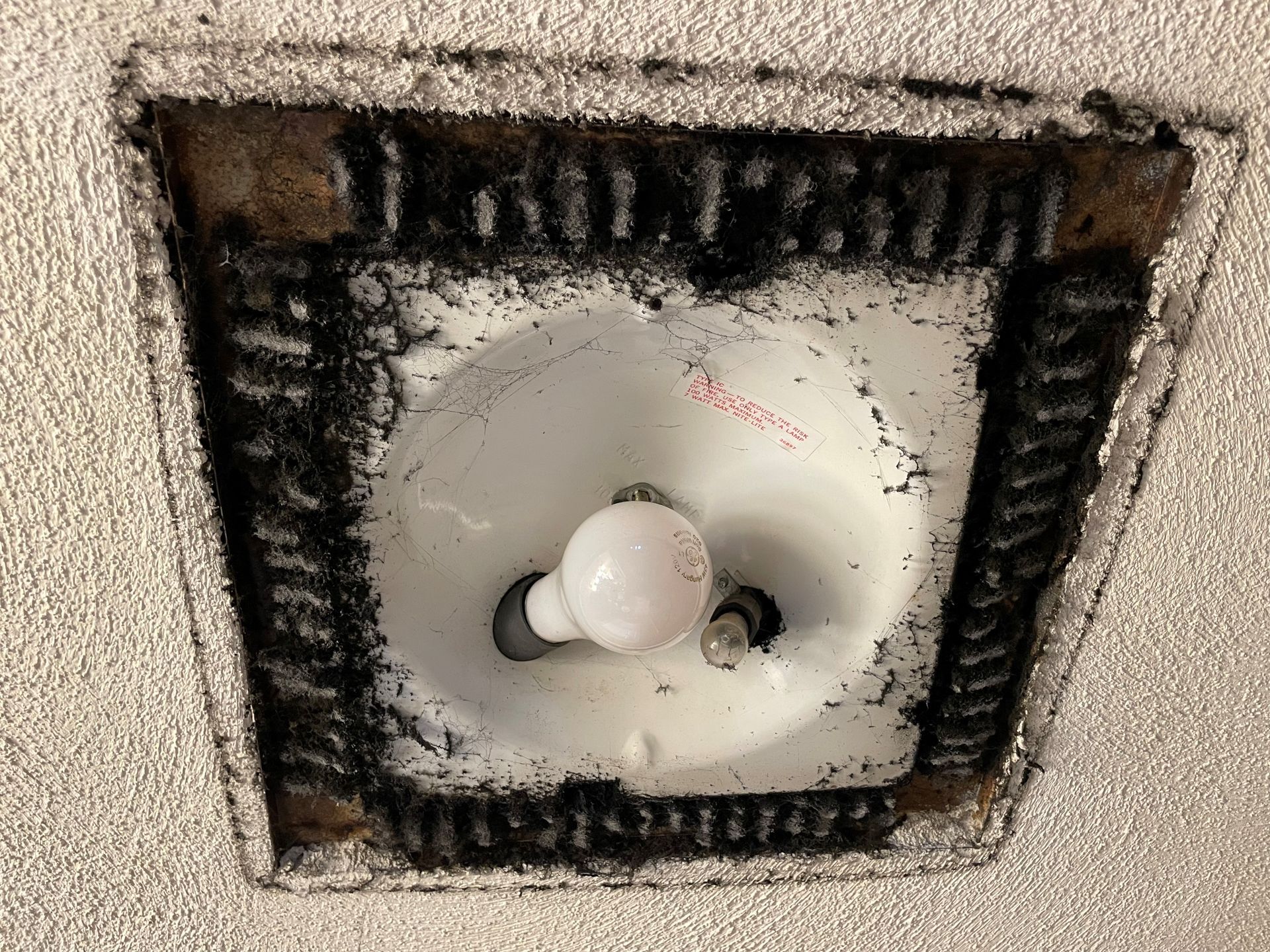 A light bulb is sitting in a hole in the wall.