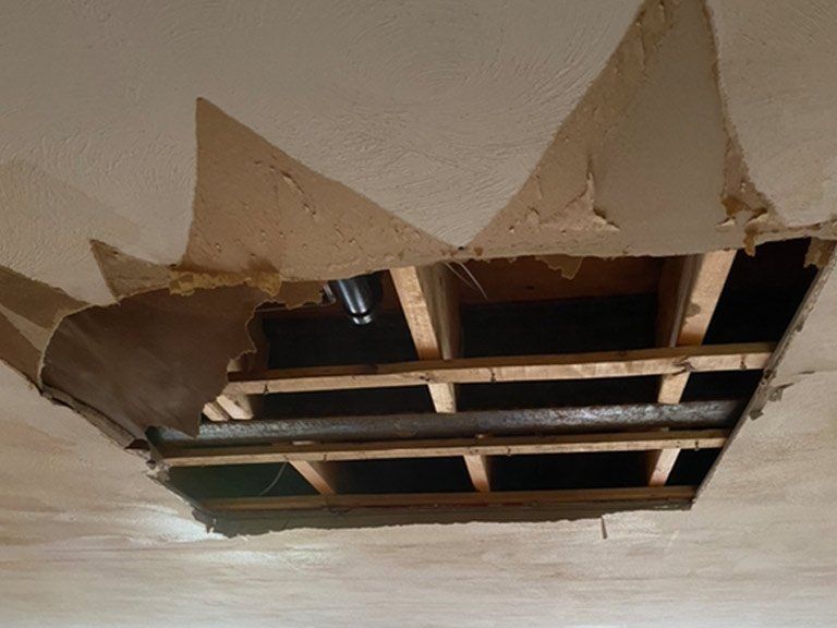 A hole in the ceiling of a room with wooden beams.