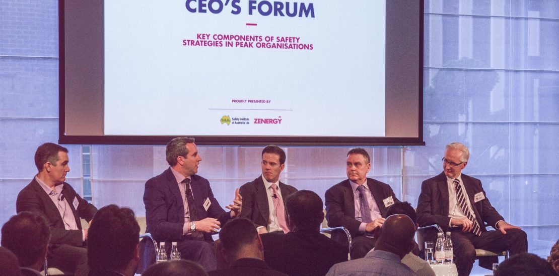 A group of men are sitting in front of a screen that says ceo 's forum