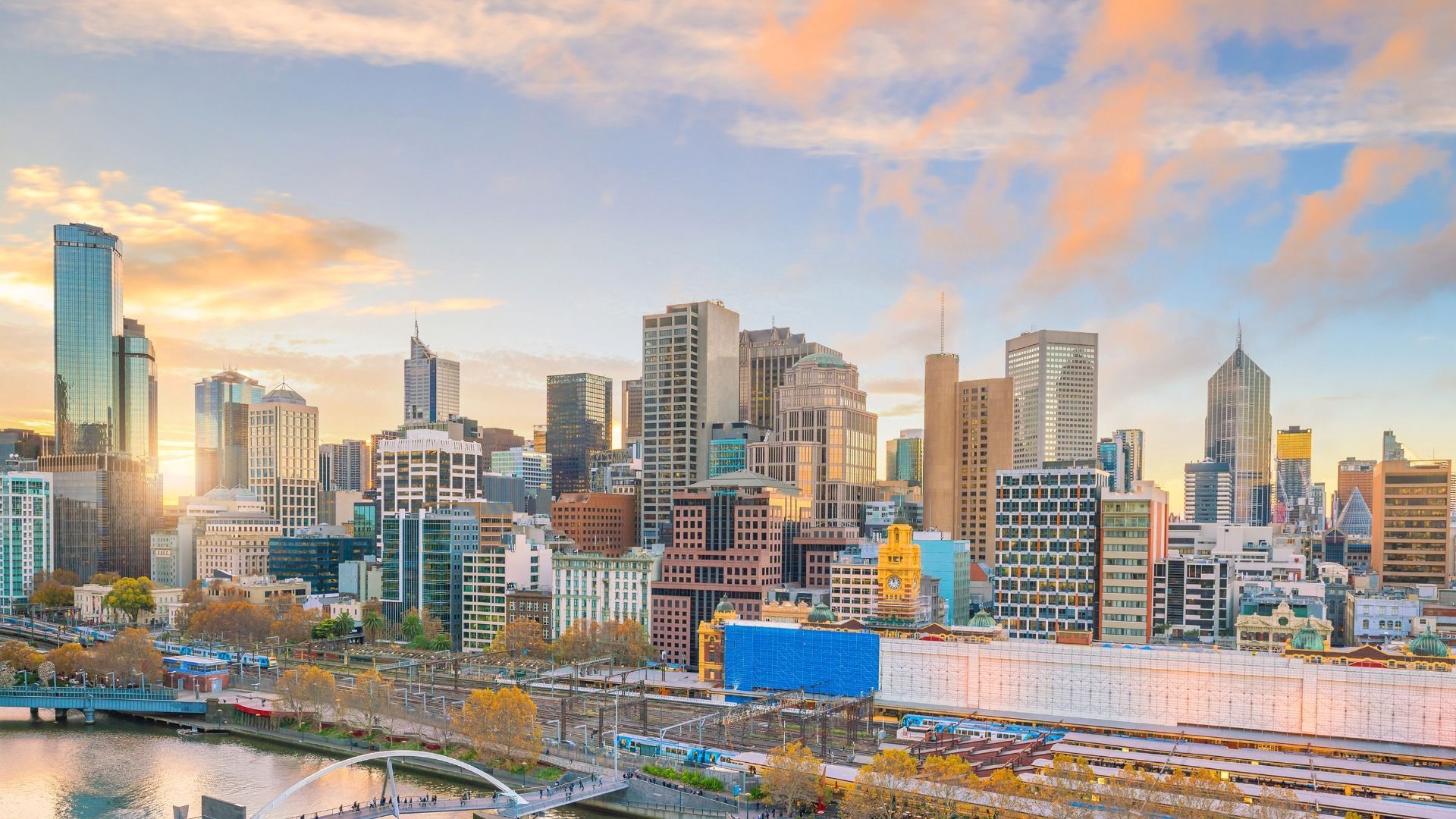 City skyline at sunset with tall modern buildings under a colorful orange and blue sky