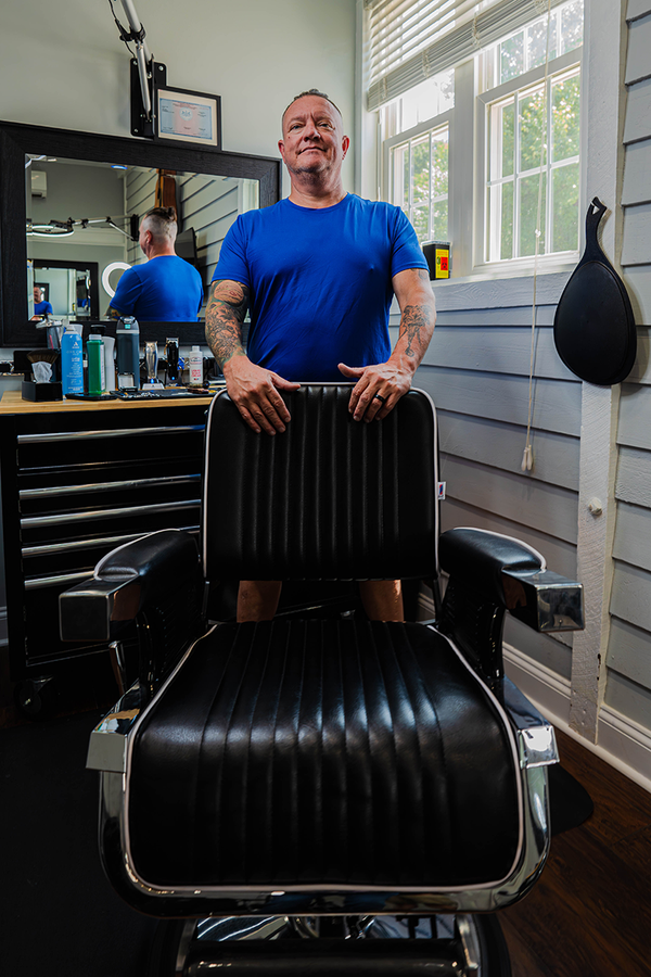 A man with a beard is getting his hair cut by a barber.