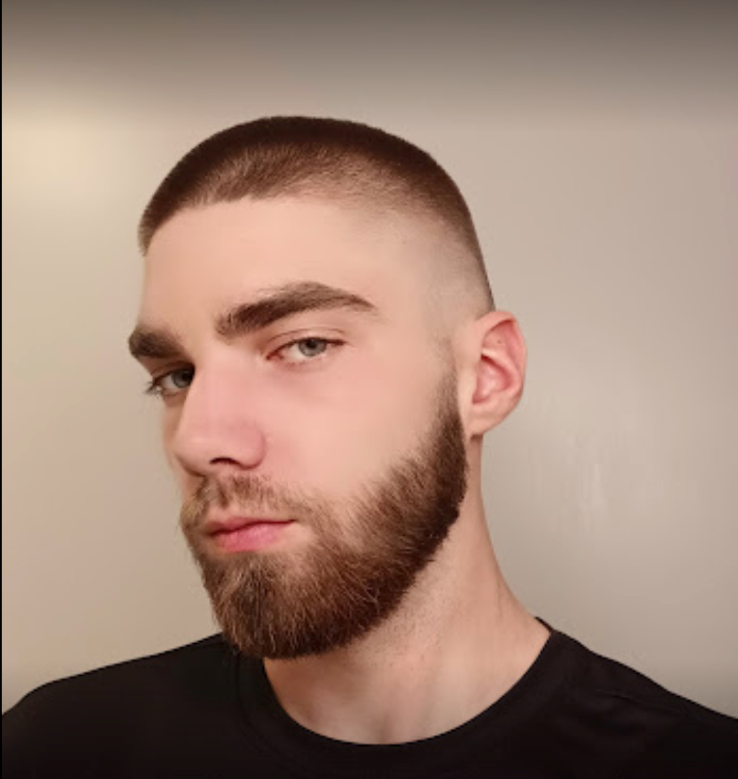 A young man with a beard is wearing a black shirt.