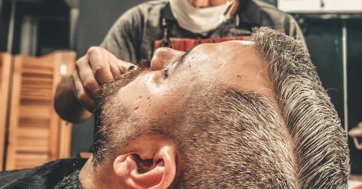 A man is getting his beard shaved by a barber in a barber shop.