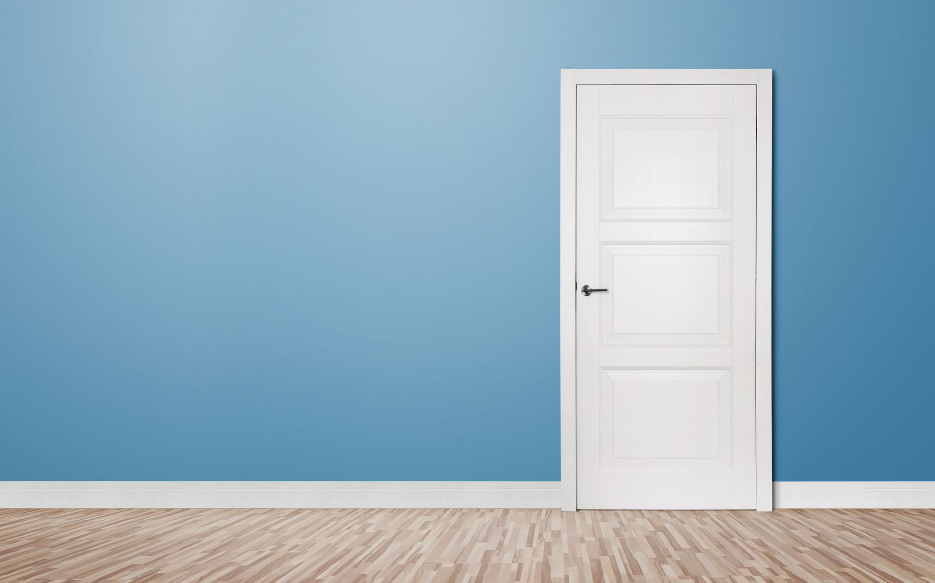 Porta bianca su parete blu con pavimento in legno.