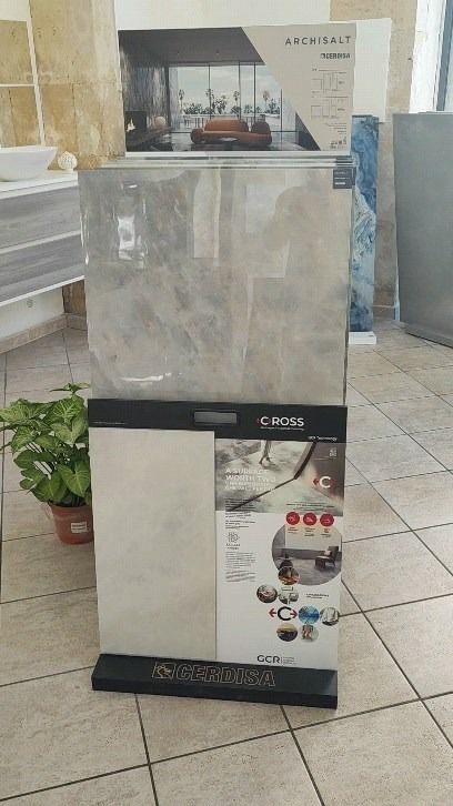 Esposizione di piastrelle in ceramica grigie e bianche con informazioni sui prodotti in un negozio.
