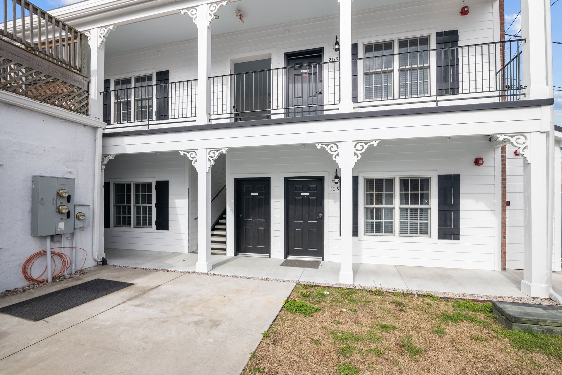 A white house with black shutters and a balcony