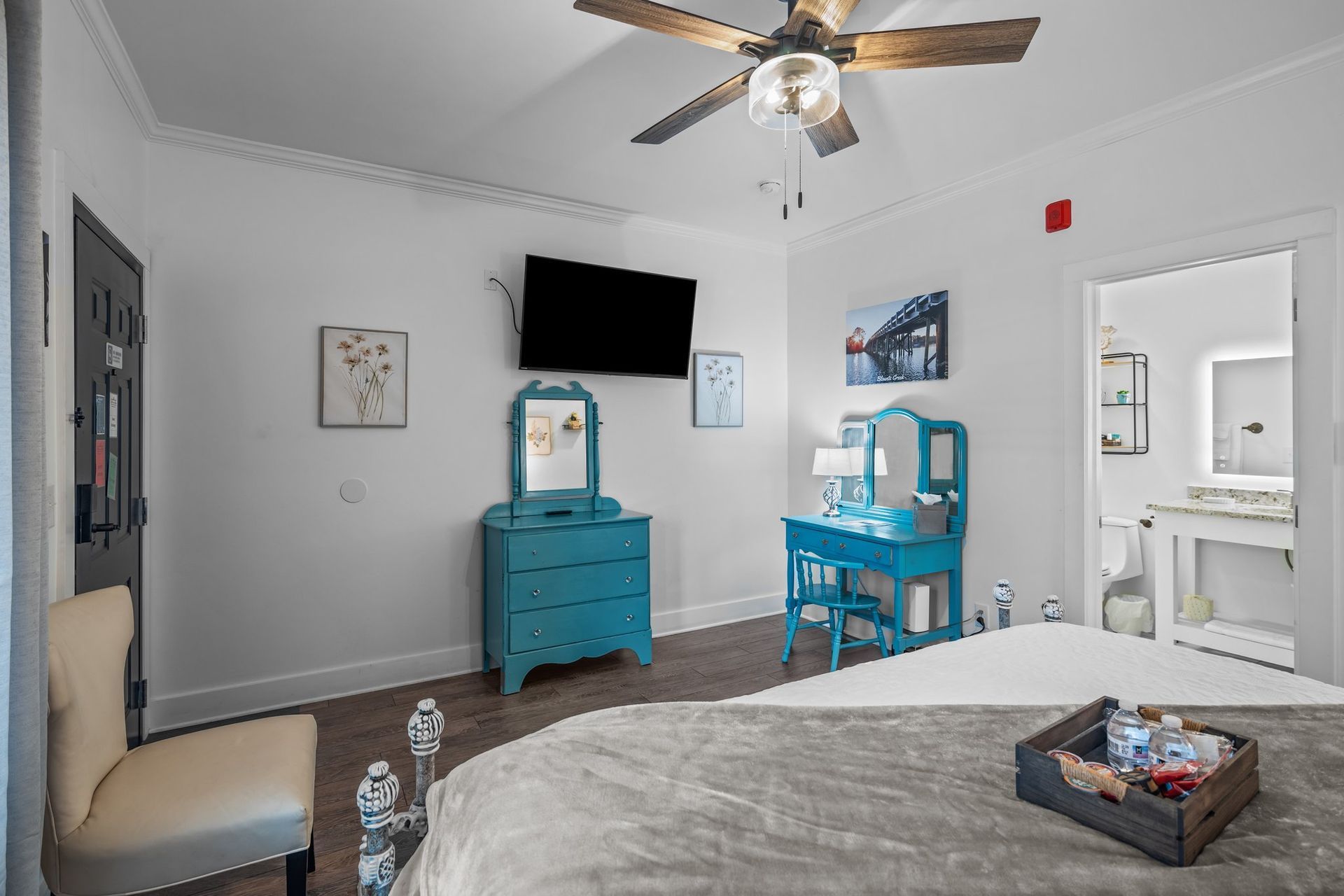 A bedroom with a bed , dresser , chair , television and ceiling fan.
