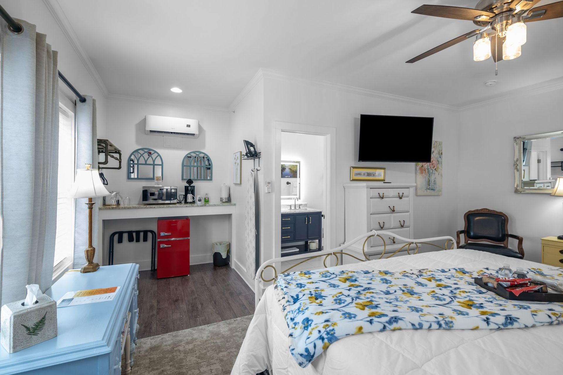 A bedroom with a bed , dresser , desk , television and ceiling fan.