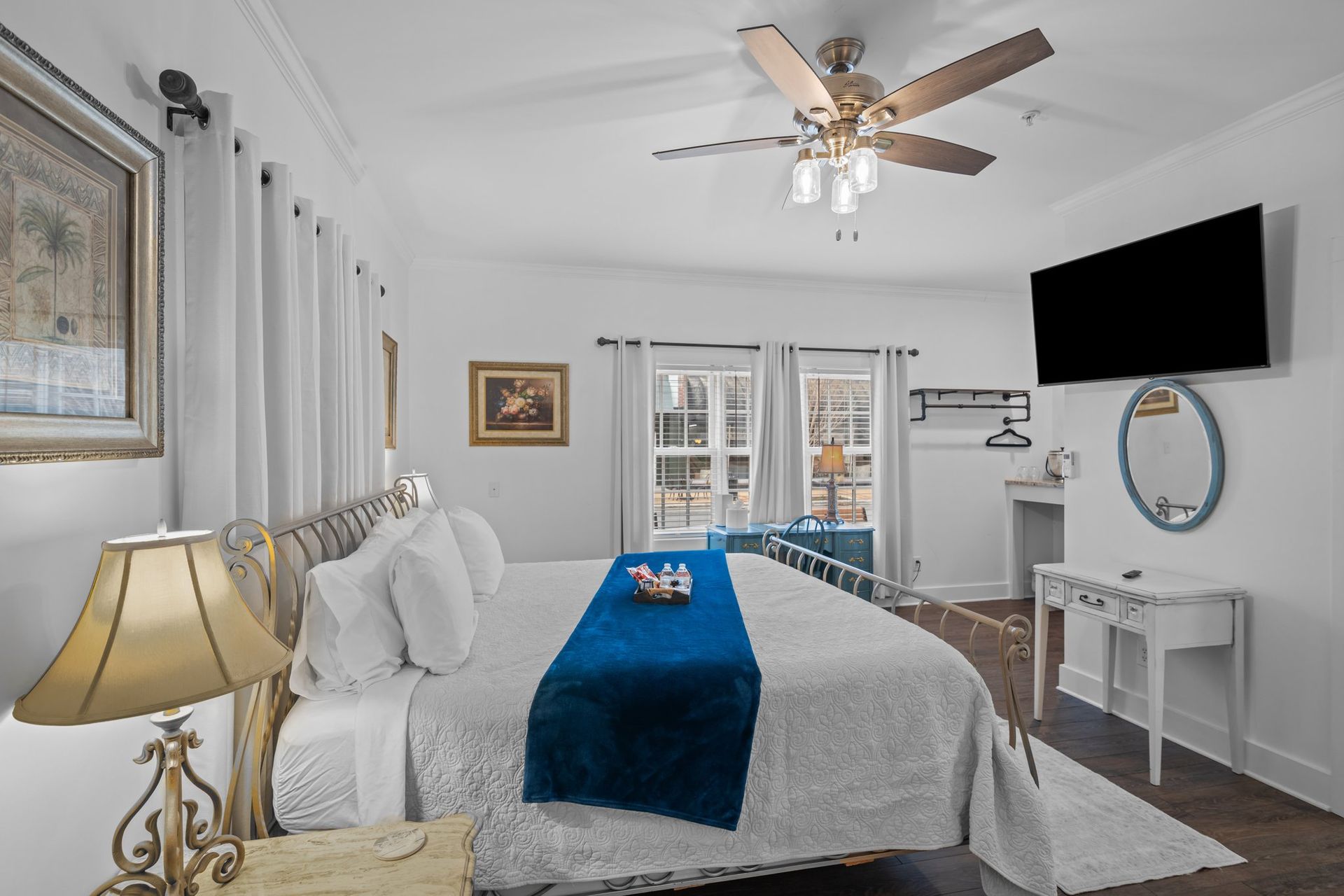A bedroom with a king size bed , television , lamp and ceiling fan.