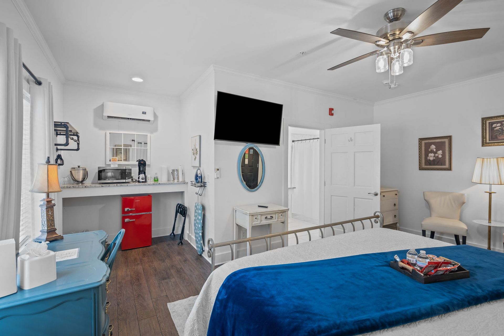 A bedroom with a bed , desk , chair , television and ceiling fan.