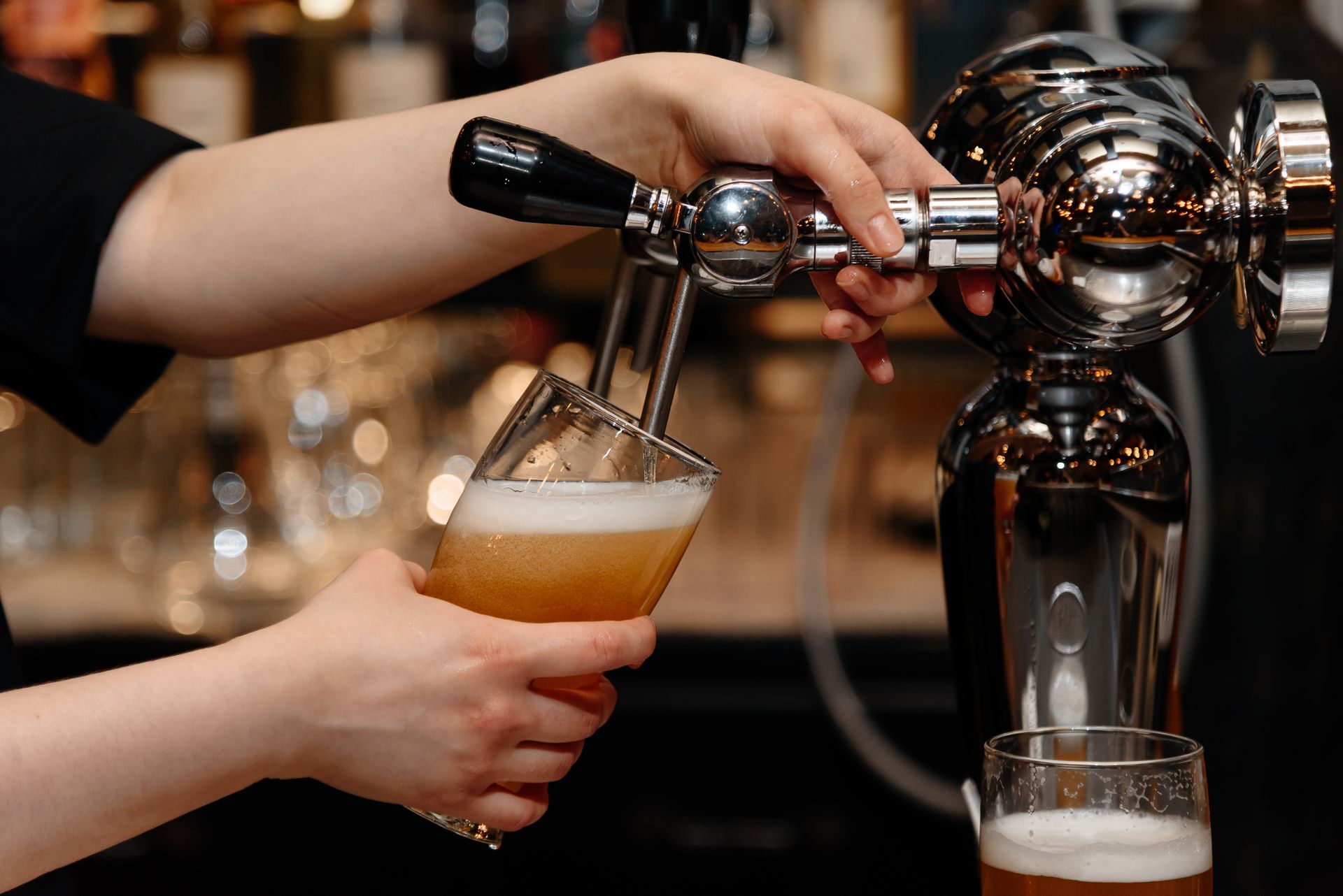 A bartender is pouring beer into a glass at a bar.